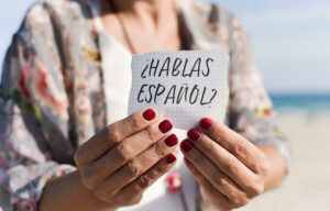 Mujer sosteniendo un papel en el que se lee: ¿Hablas español?